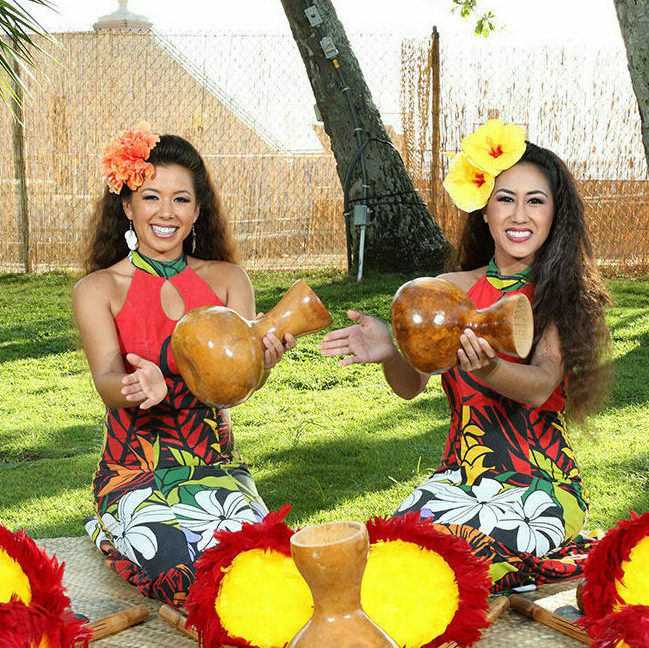 Two women hula performers hitting drums at Diamond Head Luau at Waikiki Acquarium