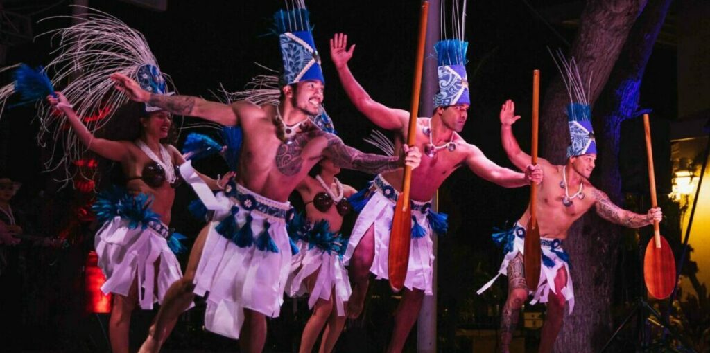 Performers in traditional costumes holding oars at Ka Moana Luau on Oahu, Hawaii