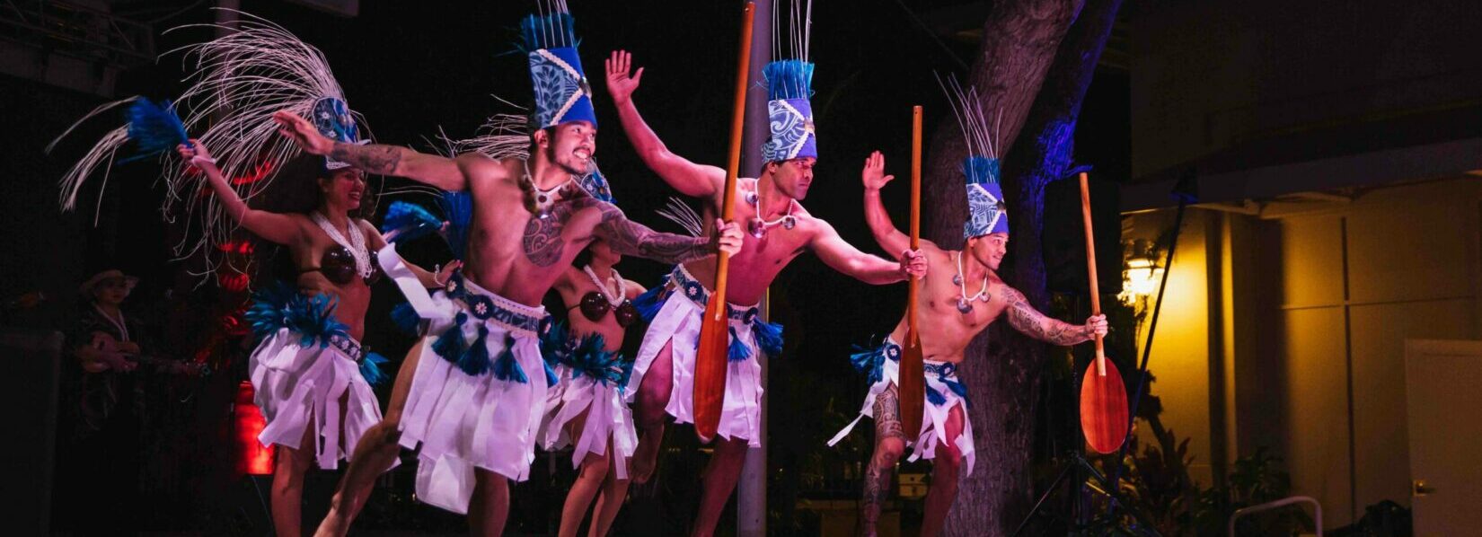 Performers in traditional costumes holding oars at Ka Moana Luau on Oahu, Hawaii