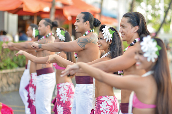 Hula dancers perform for arriving guests in pink and white Hawaiian dress. 