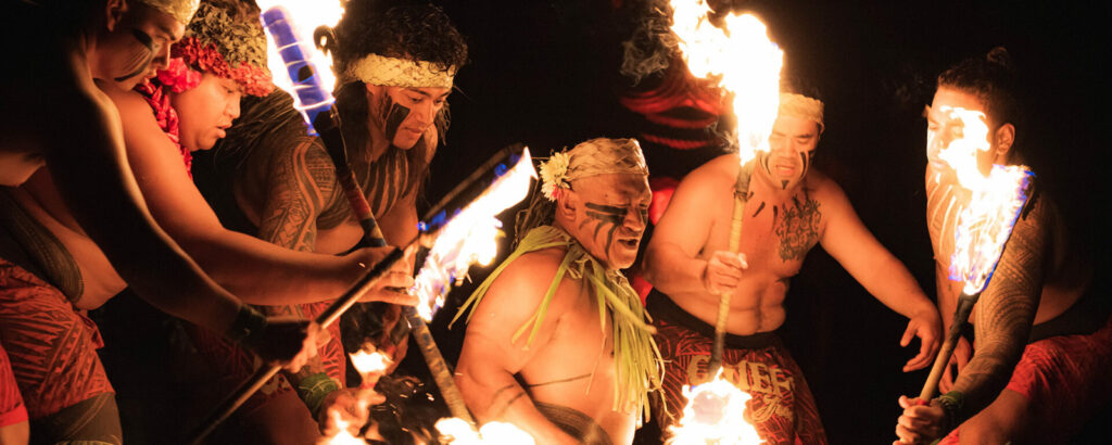Chief Sielu, the creator of Chief's Luau, is surrounded by Fire Knife dancers carrying flaming torches.
