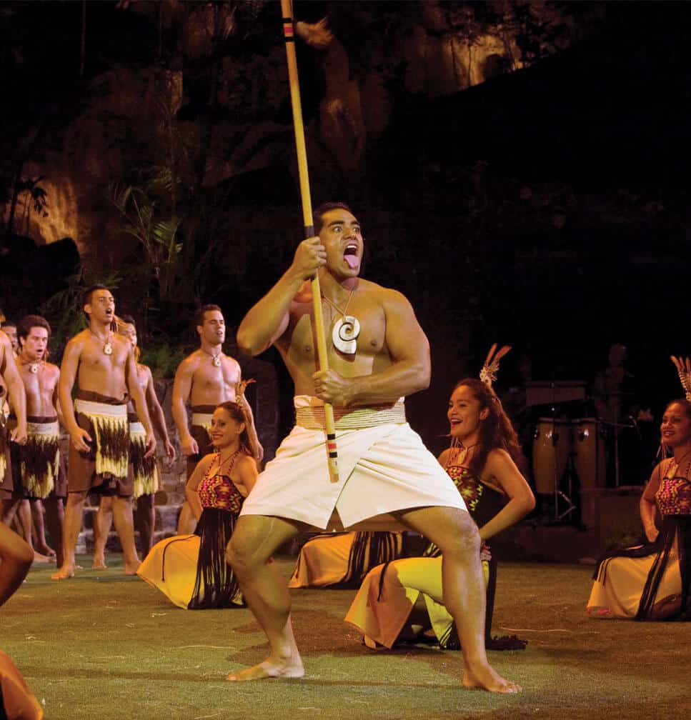 A luau performer carries a staff in front of other cast members at the luau in Laie, Hawaii.