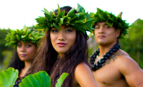 Island Breeze Luau cast members pose with bright green head dresses  and kukui nut leis. 