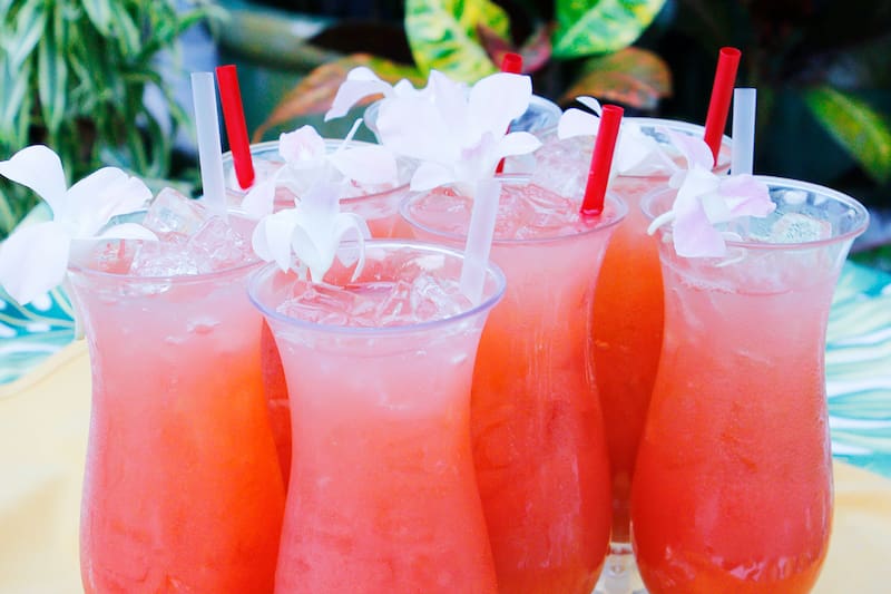 A group of pink tropical drinks in hurricane glasses.