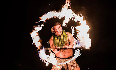 A Fire Knife dancer spins a burning torch on stage at the luau. 