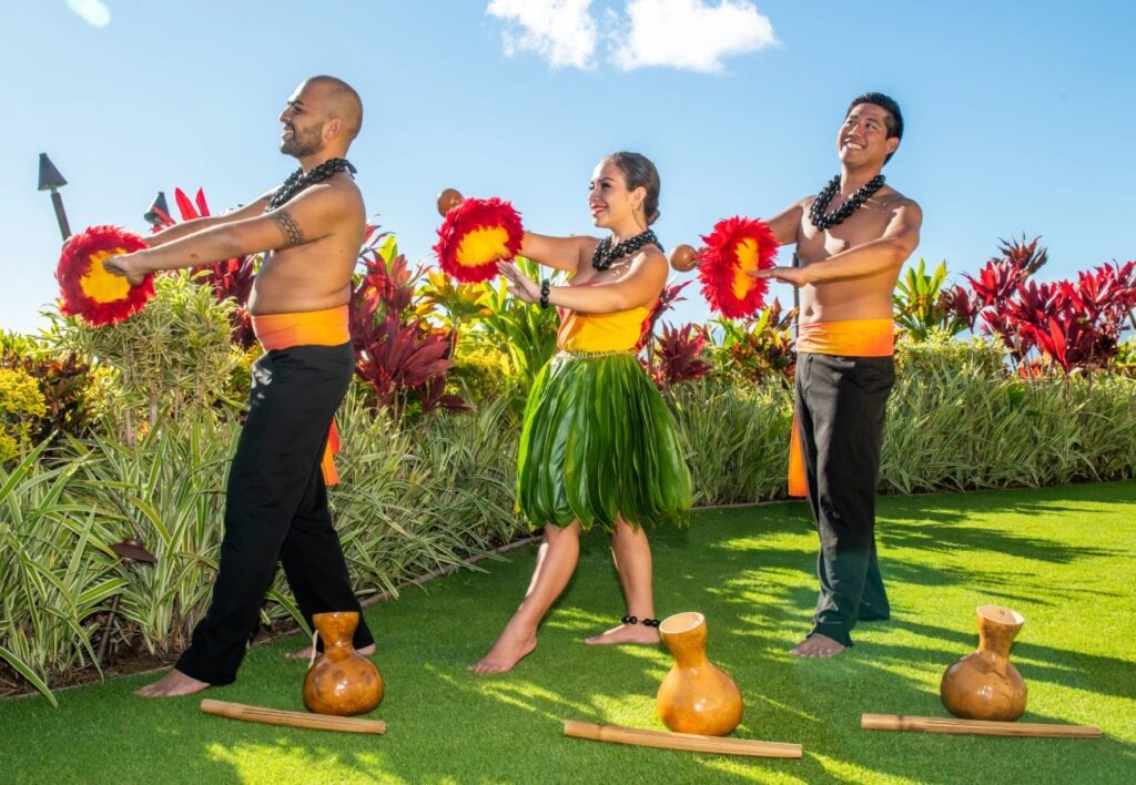 Cast members of the Myths of Maui Luau at the Royal Lahaina pose with feathered gourds on the lawn.