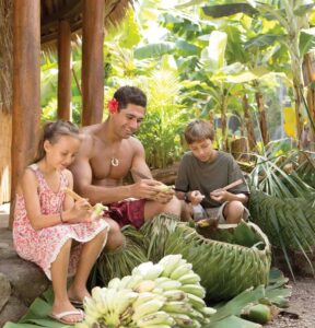 Children learn to weave a basket from coconut fronds from a man at the Polynesian Cultural center.