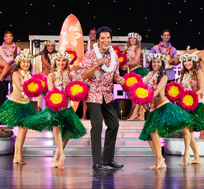 An Elvis Pressley tribute artist performs at the Rock A Hula show surrounded by hula dancers