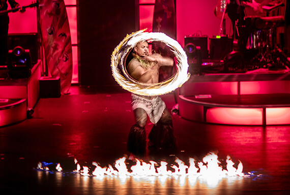 A Fire Knife dancer spins a burning torch on a stage in Waikiki. 