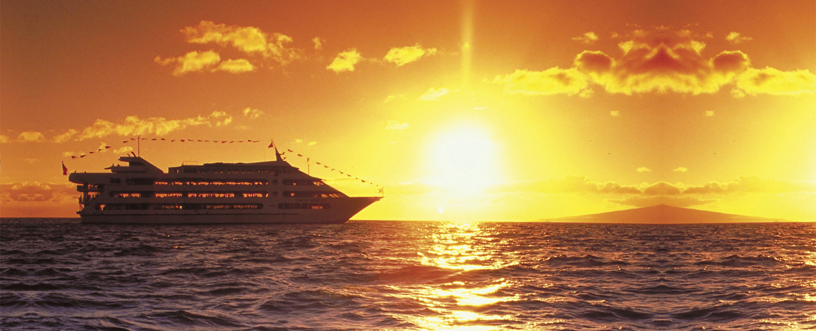 The sun sets behind the Honolulu dinner cruise ship, The Star of Honolulu.