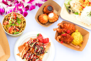 Multiple plates of food served from food venders at the Diamond Head luau. 