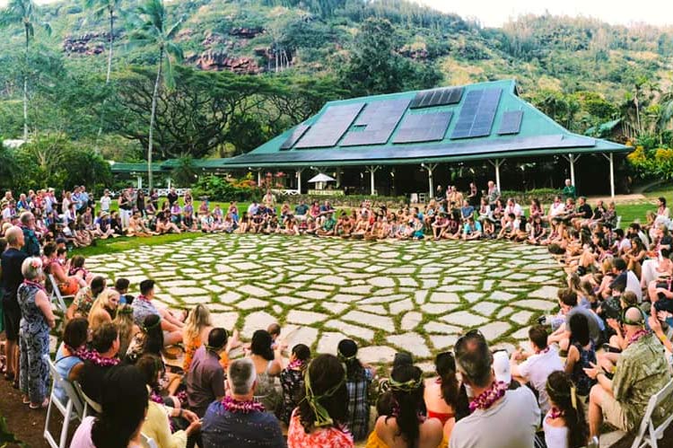 Guests gather in a circle near a pavilion at Waimea Valley.
