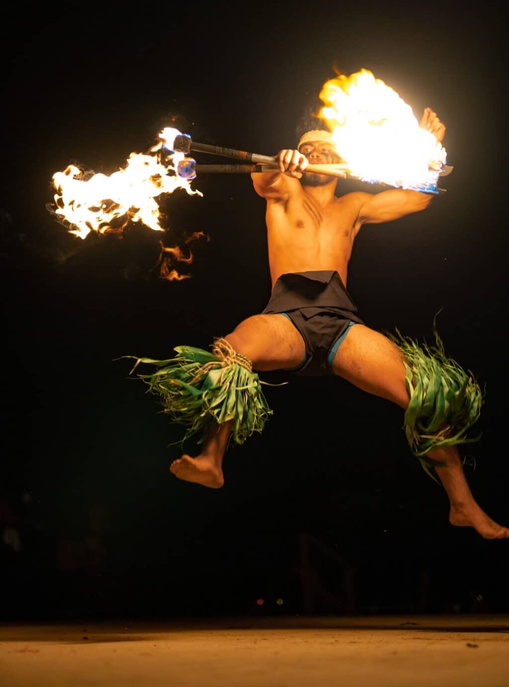 Fire knife dancer leaps into the air at Mauka Warriors Luau, one of the best luaus on Oahu.