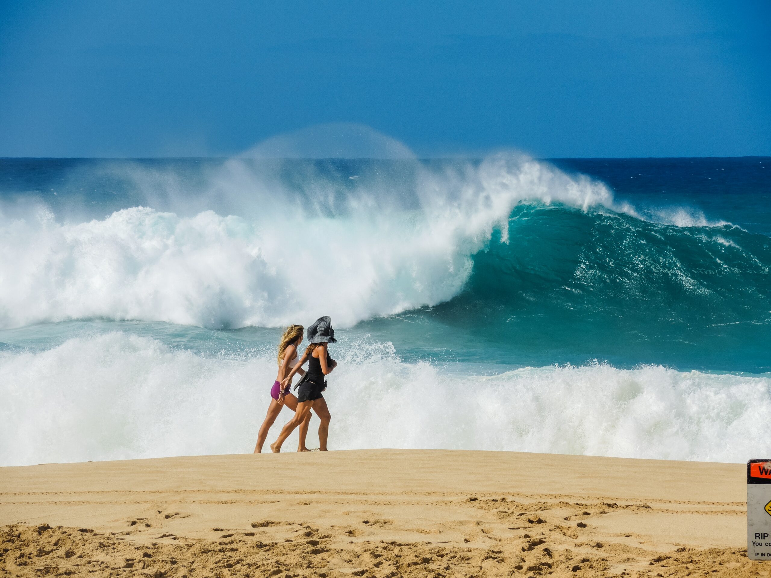 Visitors stroll past a massive wave on Oahu's North Shore.
