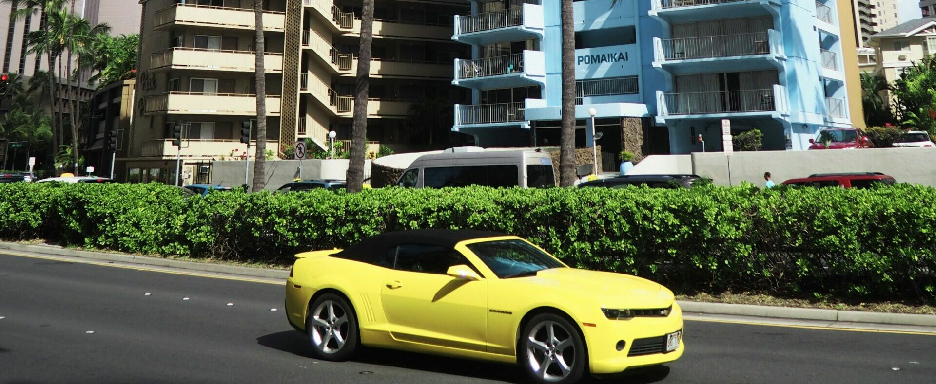 Yellow convertible drives down Ala Moana Boulevard in Waikiki Beach, Hawaii.