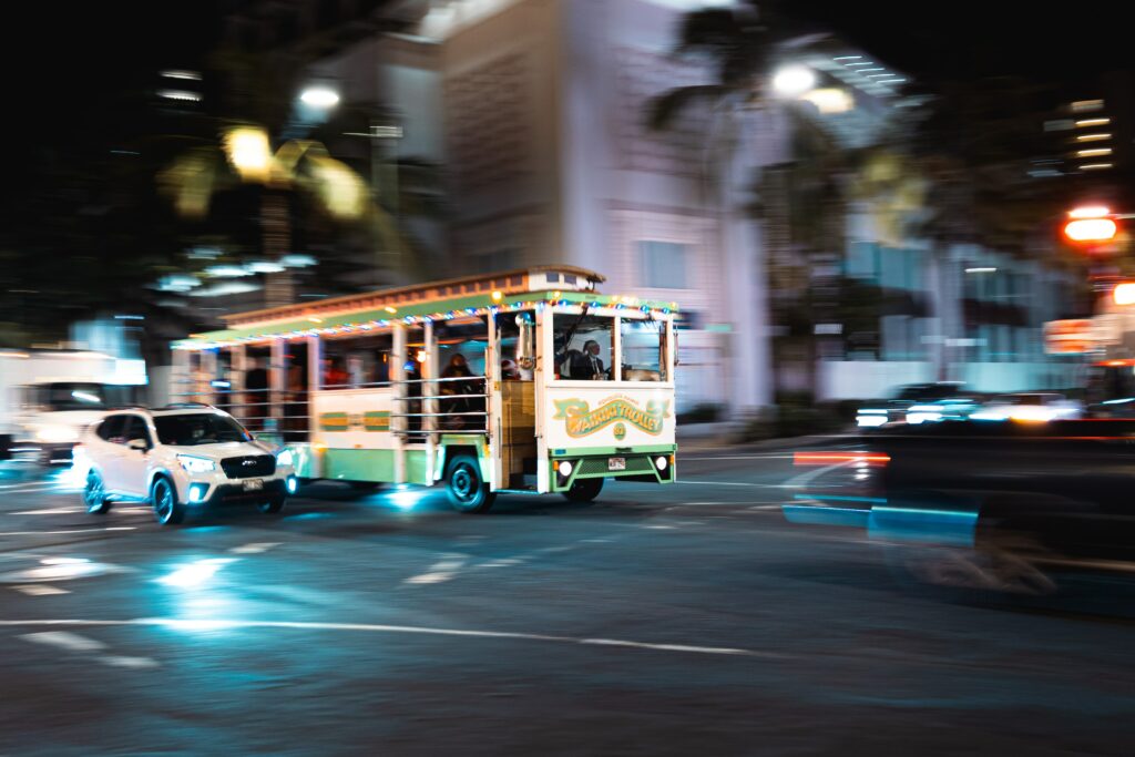 A Waikiki Trolley drives down Kalakaua Avenue at night. 