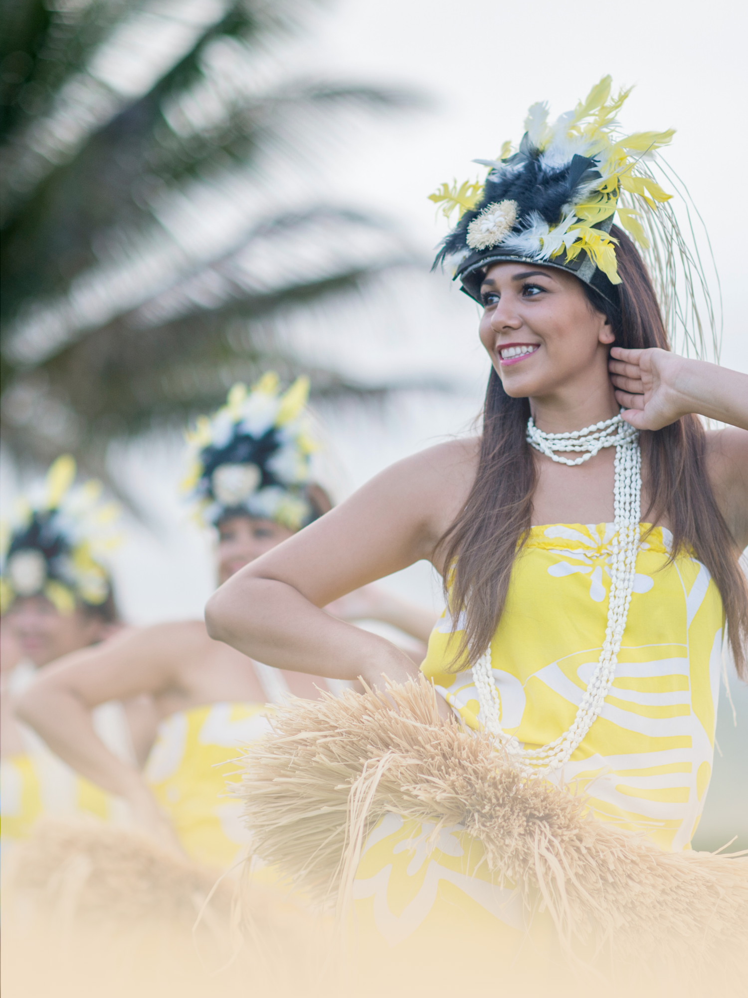 Hawaiian hula dancers dressed in yellow costume performing at a luau on Oahu. 